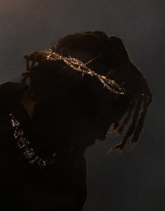 a man with dreadlocks wearing a crown of lights on his head in the dark