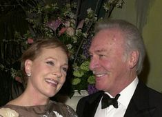 an older man and woman smile at each other while they pose for a photo together