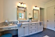 a bathroom with double sinks and mirrors in it's center wall, along with two blue stools