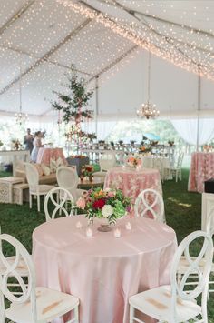 tables and chairs are set up in a tent for an outdoor wedding reception with pink linens