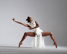 a woman in a white dress is dancing with her legs spread out and arms outstretched