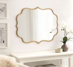 a mirror sitting on top of a white table next to a vase filled with flowers