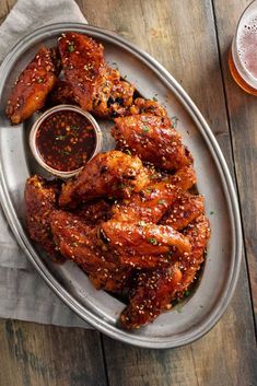 chicken wings with dipping sauce on a plate next to a glass of beer and napkin