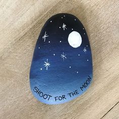 a painted rock with the words shoot for the moon on it and stars in the sky