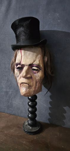 a creepy mask with a top hat on it's head sitting on a table