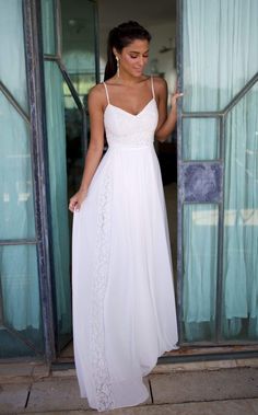 a woman in a long white dress is standing at the entrance to an open door