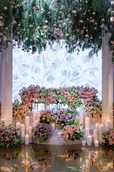 an outdoor ceremony with candles, flowers and greenery on the wall behind the altar