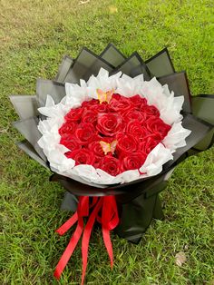 a large bouquet of red roses in the grass