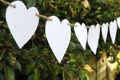 white paper hearts are hanging on a rope