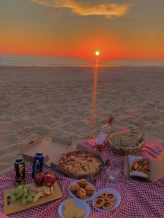 a picnic on the beach at sunset with pizza, fruit and snacks in front of it