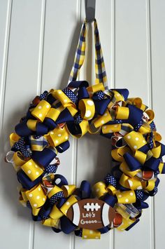 a yellow and blue wreath hanging on a door with a football tag attached to it