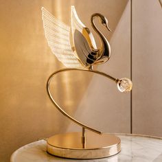 a metal swan sculpture sitting on top of a marble table