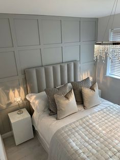 a white bed sitting in a bedroom next to a window with blinds on it's sides