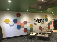 an office lobby with colorful hexagonal tiles on the wall and chairs in front of it