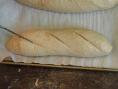 two loaves of bread sitting on top of a piece of paper next to a knife