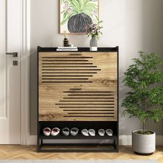 a wooden cabinet sitting next to a potted plant on top of a hard wood floor