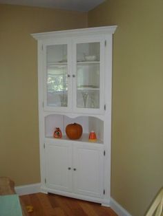 a white china cabinet in the corner of a room