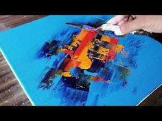 a person is painting on a blue piece of paper