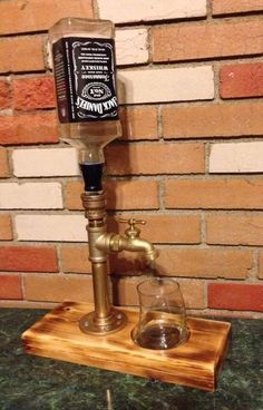 an old fashioned water faucet with a glass in front of a brick wall