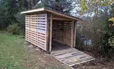 a wooden outhouse sitting on top of a lush green field next to a forest