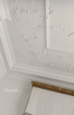 the wall paper is white and has gold trimmings on it, along with an ornate