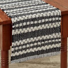 a black and white table runner on top of a wooden table with a wood leg