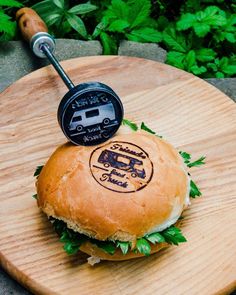 a burger on a wooden board with a grill in the middle and an air freshener attached to it