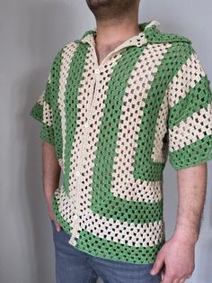 a man wearing a green and white crochet shirt with his hands in his pockets