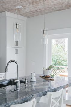 a kitchen with marble counter tops and white chairs