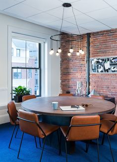 a round table with chairs around it in an office setting, next to a brick wall