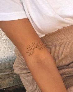 a woman's arm with a tattoo on it, and sunburst in the middle