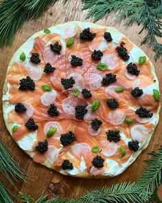 a pizza topped with salmon and black cauliflower on top of a wooden table