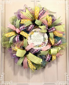 a wreath that says hello spring is hanging on the front door with ribbons and bows