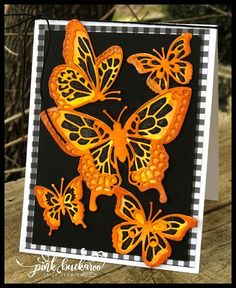 a card with orange butterflies on black and white checkered paper, sitting on a wooden table