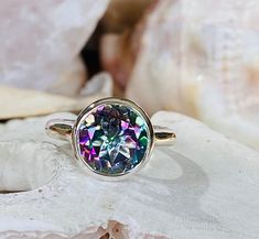 This modern bezel set ring contains a 4.00 ct. natural mystic topaz. The center stone measures 10mm and the band is approximately 2.5mm wide. The ring is available in sterling silver and 14k white, yellow, or rose gold. The mounting is a modern, elegant setting with a high polish finish. Please send me a message if you need a size not listed. This ring can be customized with any color center stone. All items are handmade by me in my shop in Manalapan, NJ. Please message me with any questions. Sh Iridescent Topaz Gemstone Ring, Green Topaz, Mystic Topaz Ring, Bezel Set Ring, Bezel Ring, Morganite Ring, Set Ring, Mystic Topaz, Topaz Gemstone