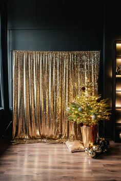 a small christmas tree in front of a gold curtain with lights on the top and bottom