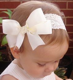 a baby girl wearing a white headband with a large bow on it's side