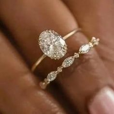 a woman's hand holding a ring with a diamond on it and two diamonds in the middle