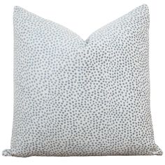 a blue and white pillow with small dots on the front, sitting on a white background