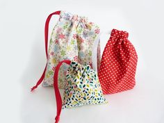 three drawstring bags are lined up on a white surface, one is red and the other is green