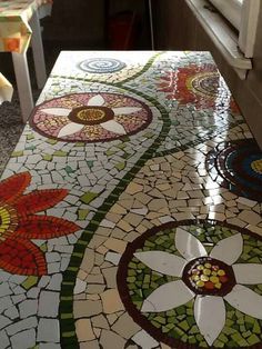 a kitchen counter covered in colorful tiles and flowers on it's side, with the top half painted white