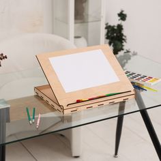 a glass table topped with a wooden easel next to a white couch