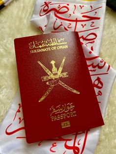 a red and yellow islamic passport sitting on top of a white tablecloth with writing