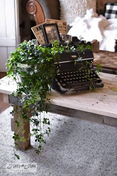 an old fashioned typewriter sitting on top of a table next to a potted plant