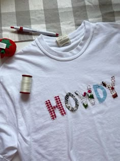 a white t - shirt with the word hod on it next to spools of thread