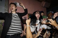 a group of people standing around each other with their hands in the air and holding cell phones