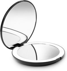 the compact mirror is open to show it's reflection on the surface and its lid