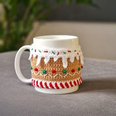 a crocheted coffee mug with white frosting and candy canes on it