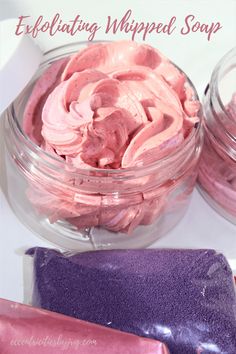 pink whipped cream in a glass bowl next to two purple candy bars on a white surface