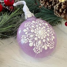 a purple ornament sitting on top of a wooden table next to pine cones